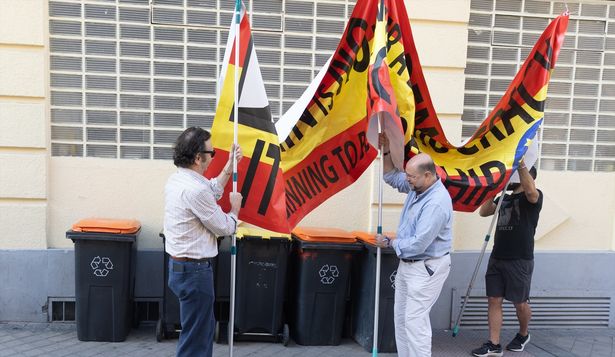 Varios hombres sujetan una pancarta contra el presidente del Gobierno en el colegio de Nuestra Señora del Buen Consejo, donde votaron Pedro Sánchez y Begoña Gómez