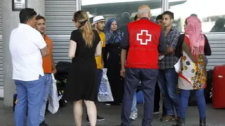 Imagen de archivo de un miembro de Cruz Roja con un grupo de refugiados en el aeropuerto de Madrid-Barajas