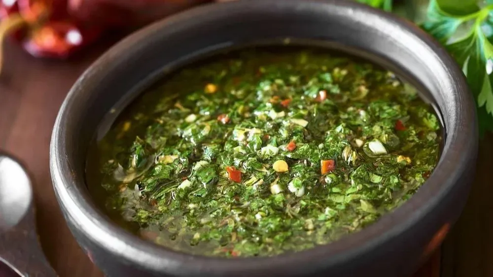 El chimichurri es una mezcla de perejil finamente picado, orégano, chile molido y ajo mezclado con vinagre y aceite vegetal