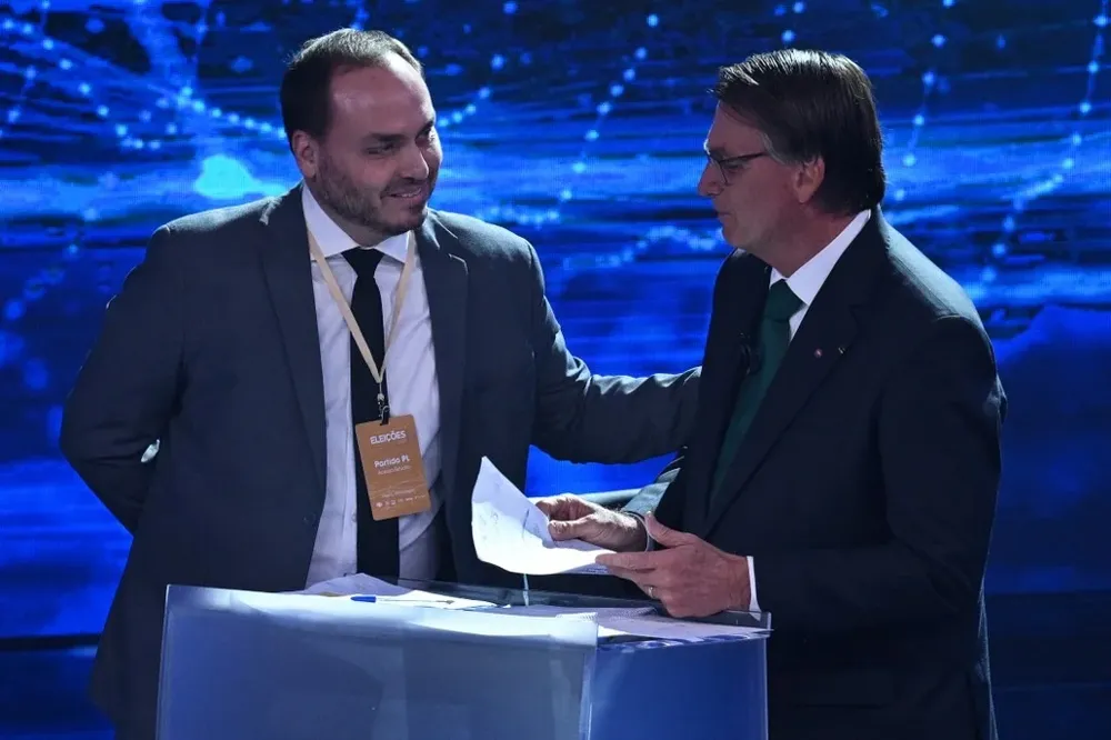 Carlos y Jair Bolsonaro durante el debate presidencial que enfrentó al exmandatario con el actual presidente Luiz Inácio Lula da Silva.