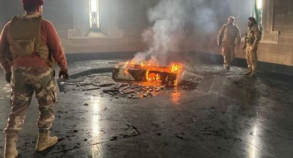 Combatientes sirios observan el fuego en la tumba de Hafez al Assad.