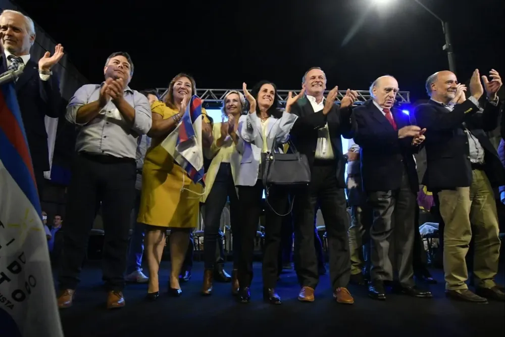 Líderes políticos, incluidos ministros del actual gobierno, aplauden sobre el escenario