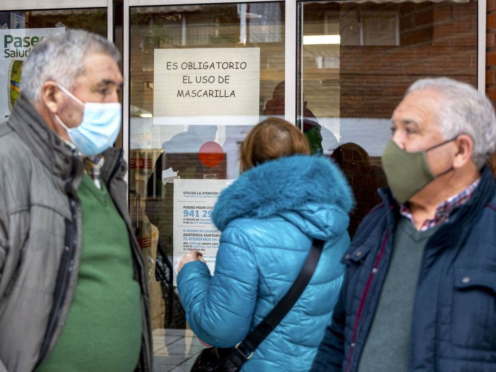 Personas utilizan mascarillas frente a un centro de salud.