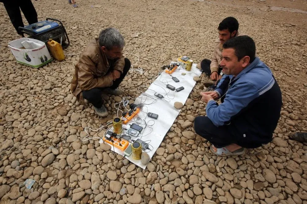 Iraquíes desplazados cargan sus celulares en el campamento de refugiados de Hamam al-Alil. Iraq