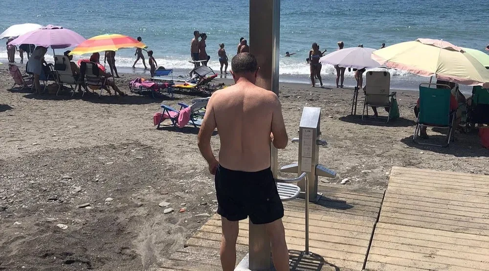 Un hombre en la ducha de una playa de Málaga
