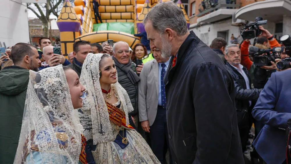 Felipe VI dialoga con dos falleras en su visita a Valencia.