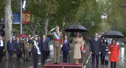 El Rey Felipe VI, la reina Letizia y la princesa Leonor, bajo la lluvia en el comienzo del desfile por el Día de la Hispanidad.