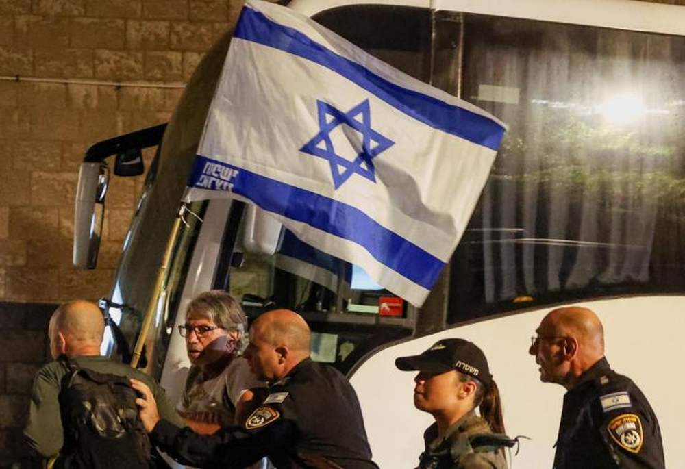 Agentes de policía detienen a manifestantes, uno de ellos con una bandera israelí, durante una protesta para exigir la liberación inmediata de los rehenes secuestrados.