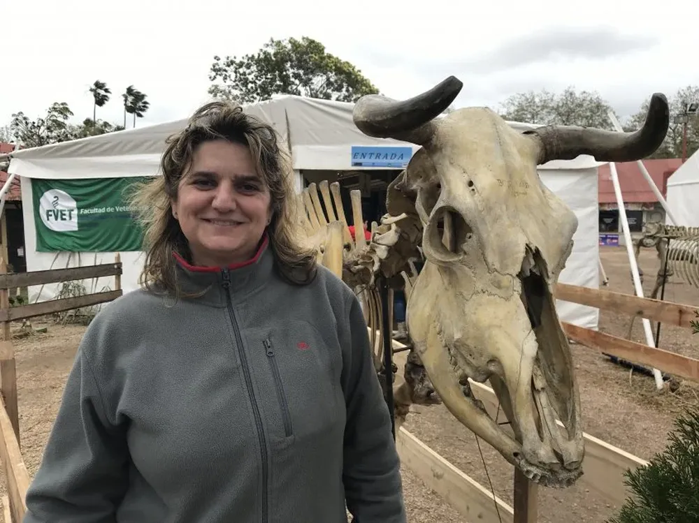 Una de las anfitrionas junto a un esqueleto de bovino, en el acceso al stand.