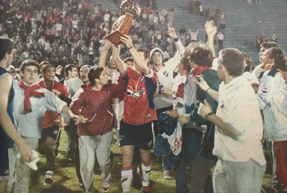 Alejandro Lembo da la vuelta olímpica rodeado de hinchas en 2001, en el Campus de Maldonado