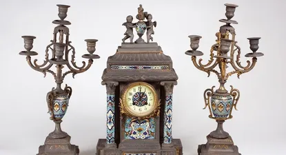 El Observador | Garniture francesa, en petit bronce y cloisonne, en variado colorido, con un reloj de cuerpo rectangular, con esfera esmaltada de números arábigos y cristal