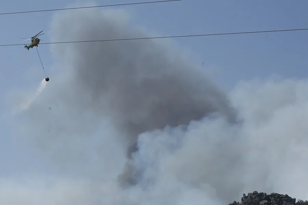 Efectivos trabajan en la extinción del incendio declarado en la sierra de la Plata, cerca de la playa de Bolonia en Tarifa (Cádiz). EFE