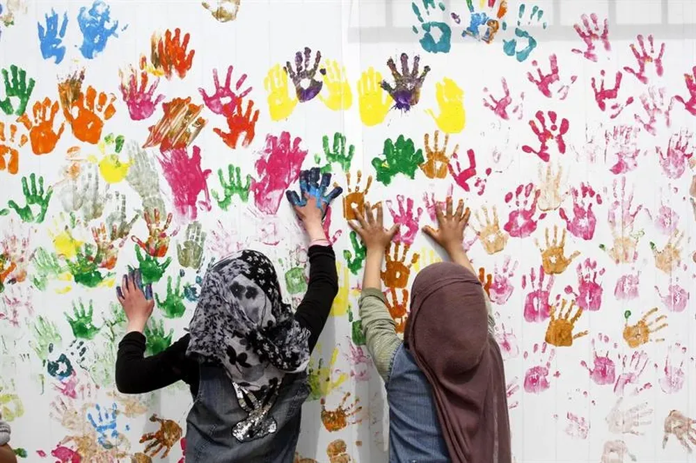 Jordania- Dos refugiadas sirias pintan un mural con sus manos en el campo de refugiados de Zaatri, cerca de Mafraq