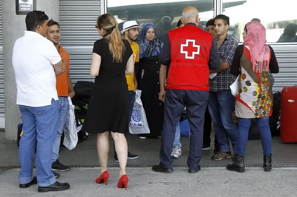 Imagen de archivo de un miembro de Cruz Roja con un grupo de refugiados en el aeropuerto de Madrid-Barajas