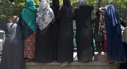 Las mujeres afganas desplazadas internamente, que huyeron de la provincia del norte debido a la batalla entre los talibanes y las fuerzas de seguridad afganas, se reúnen para recibir alimentos gratuitos distribuidos por hombres chiítas