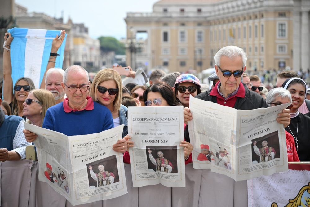 Feligreses y turistas revisan la edición especial del diario vaticanista LOsservatore Romano.