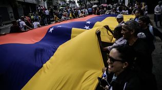 Manifestantes despliegan la bandera de Venezuela