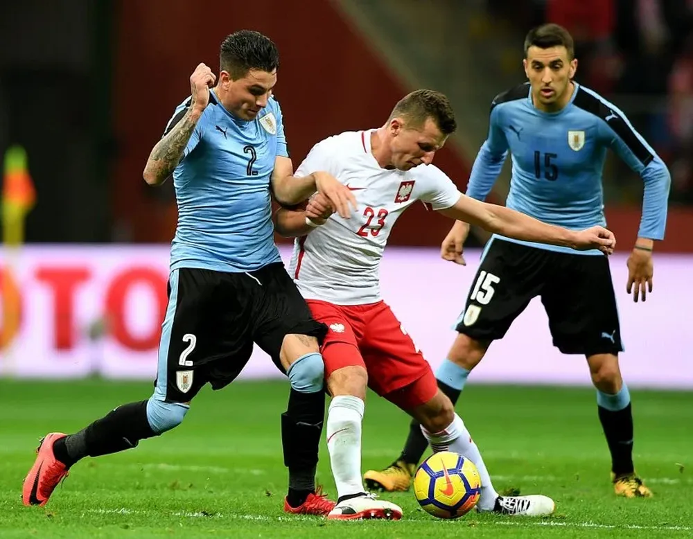 Polands Kamil Wilczek (C) vies for the ball with Uruguays Jose Maria Gimenez (L) and Matias Vecino during the friendly football match between Poland and Uruguay at National stadium in Warsaw, Poland, on November 10, 2017.  / AFP / JANEK SKARZYNSKI