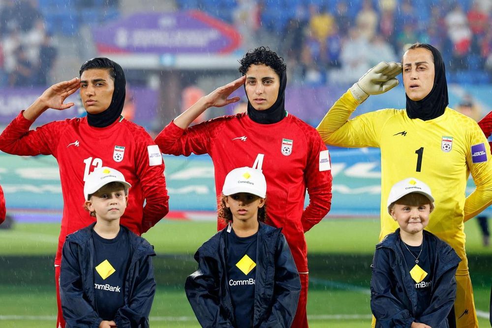 La portera Raha Yazdani y las jugadoras Melika Motevalli y Fatemeh Amineh hacen el saludo militar durante el himno nacional de Irán.