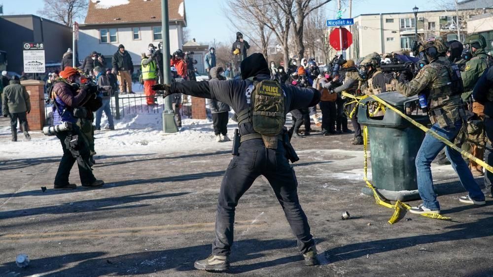 Un agente federal lanza una granada de gas lacrimógeno mientras los manifestantes se enfrentan a la policía tras el tiroteo.