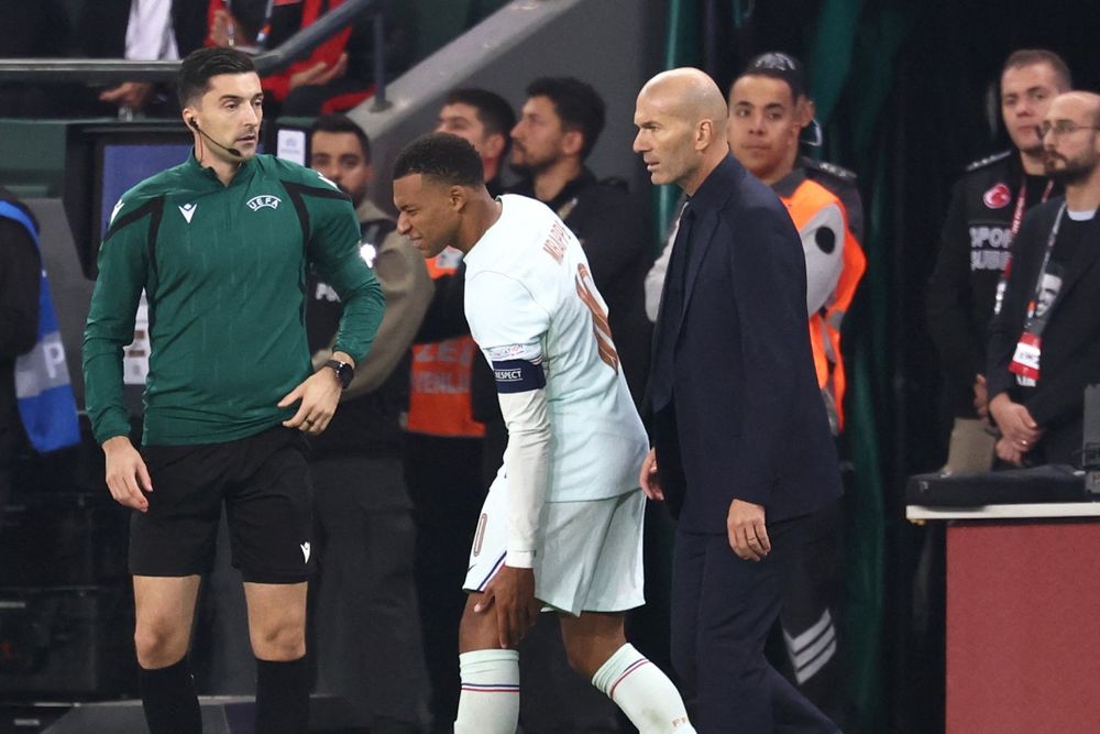 Kylian Mbappé se retira de la cancha al lado del técnico de Francia, Zinedine Zidane, tras su lesión en la rodilla con un claro gesto de dolor