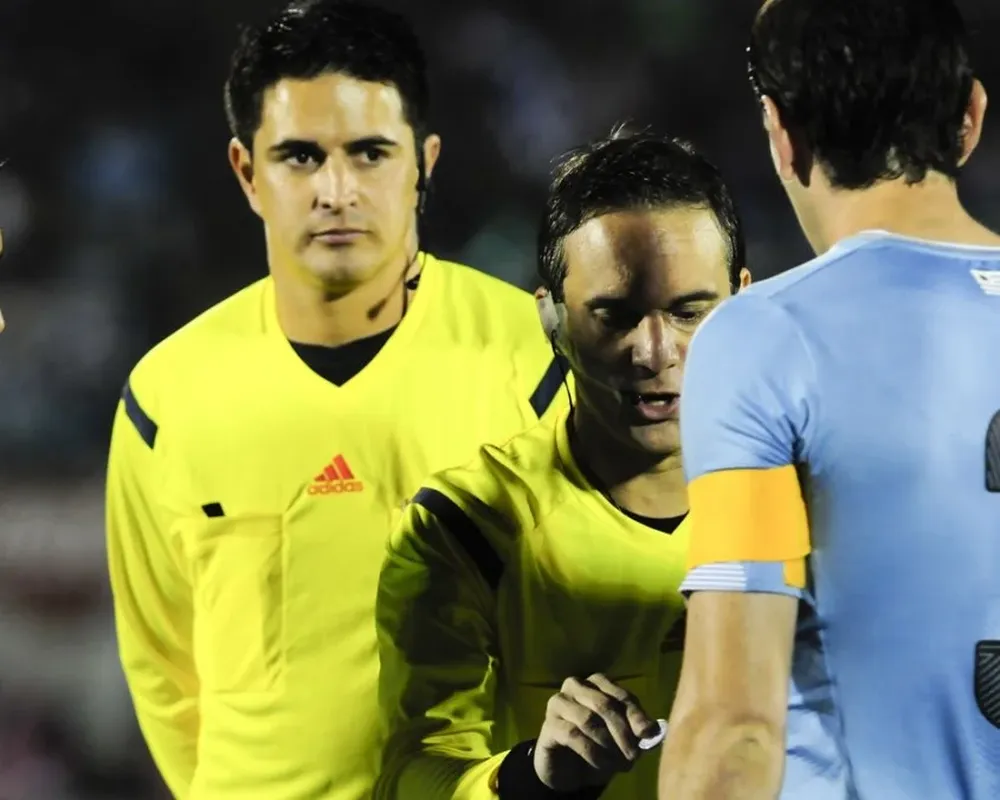 El árbitro argentino Patricio Loustau y el capitán uruguayo Diego Godín