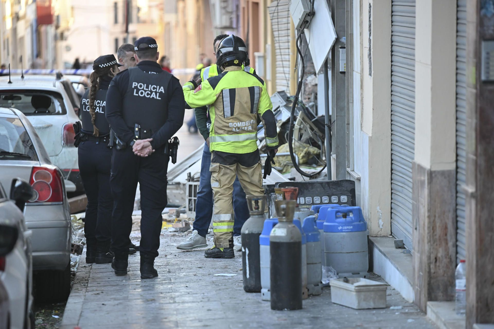 Policía y bomberos locales puerta del bar afectado, con más bombonas de gas sacadas del establecimiento.