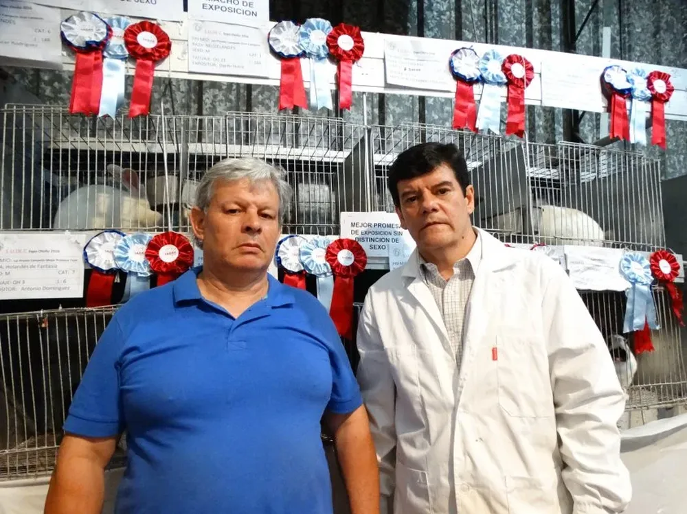 Dardo Dutra y José Luis Techeira delante de las jaulas con los mejores conejos.