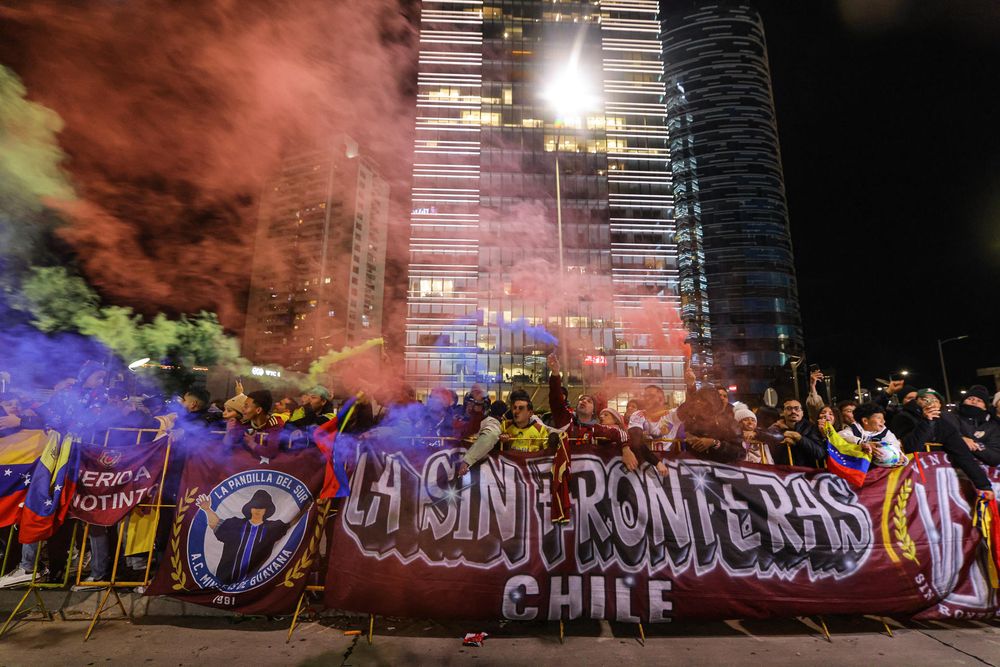 Hinchas sostienen bengalas durante el recibimiento a la selección de fútbol de Venezuela este lunes, frente al Hotel Hilton Garden en Montevideo
