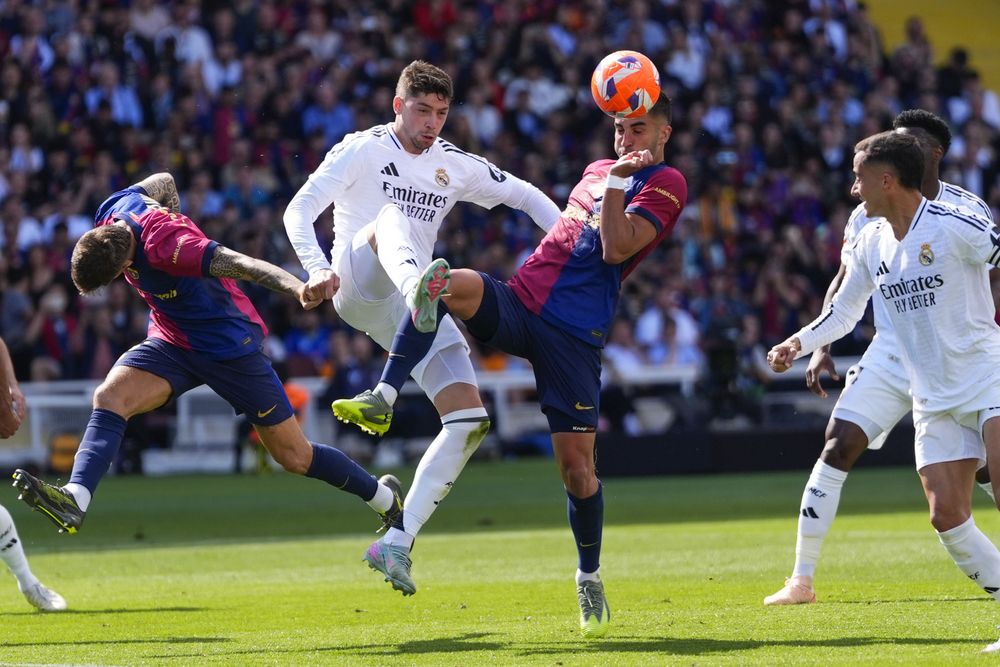 Ferrán Torres de Barcelona y el mediocampista de Real Madrid Federico Valverde disputan el balón durante el clásico de LaLiga de España