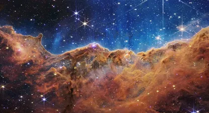 Esta imagen publicada por la NASA el 12 de julio de 2022 desde el Telescopio espacial James Webb (JWST) muestra un paisaje de montañas y valles salpicado de estrellas brillantes que en realidad es el borde de una región cercana, joven y de formación estelar. llamado NGC 3324 en la Nebulosa Carina. Capturada en luz infrarroja por el JWST, esta imagen revela por primera vez áreas de nacimiento estelar previamente invisibles.