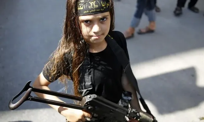 Franja de Gaza. Una niña sujeta un arma junto a luchadores palestinos