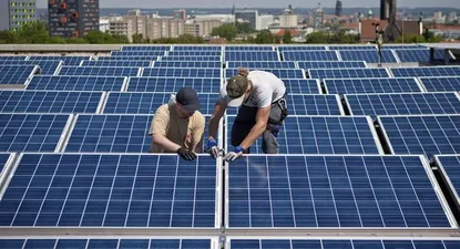 Alemania- Dos operarios instalan un panel solar en el techo de la universidad de Dresde