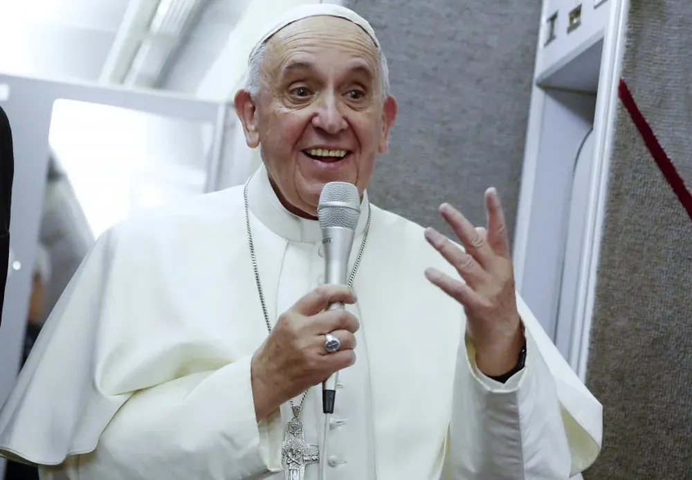 Pope Francis address the crew and press core aboard the papal plane while en route to Italy on September 28, 2015. AFP PHOTO / POOL / TONY GENTILE