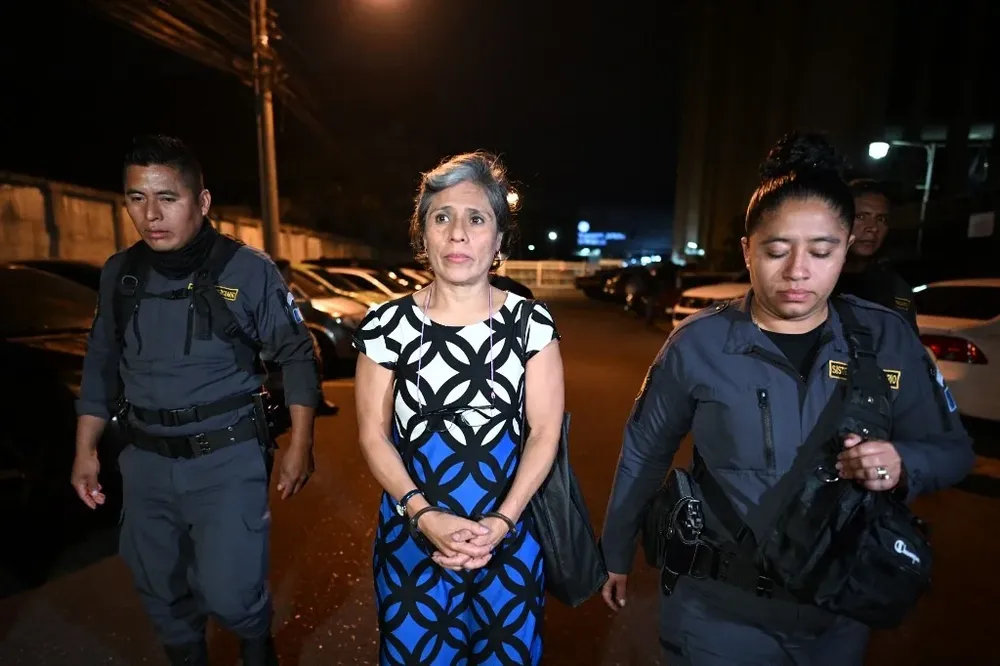 La exfuncionaria de la ONU Claudia González sale de tribunales escoltada por dos policías.