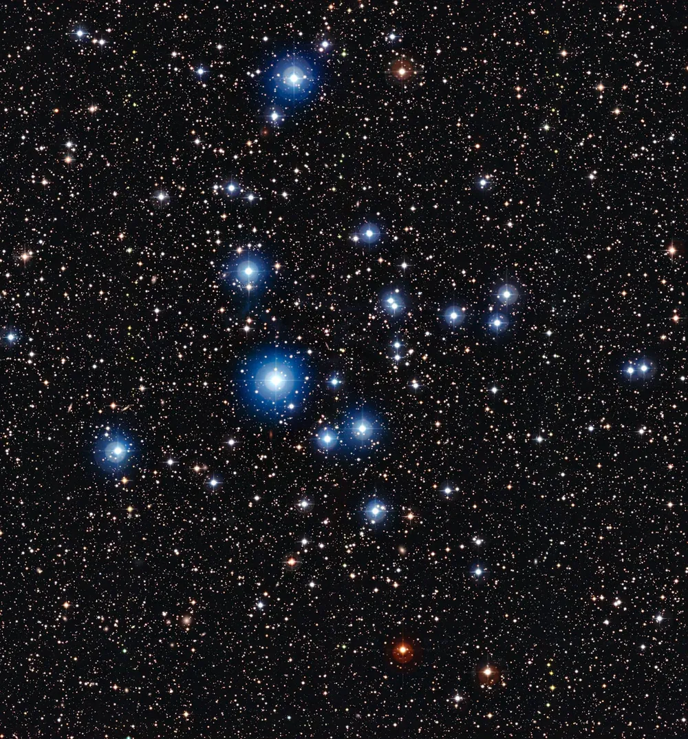 La imagen captada por el telescopio MPG/ESO del Observatorio La Silla, en Chile, muestra las estrellas brillantes del cúmulo NGC 2547. Detrás de los astros con mayor brillo, se pueden ver otras galaxias remotas con forma de espiral