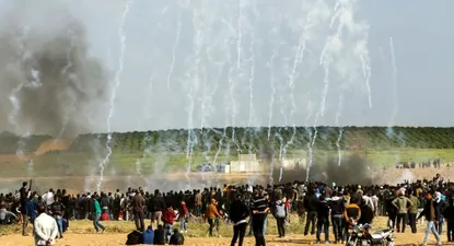 Manifestantes palestinos corren para protegerse del gas lacrimógeno lanzado por las fuerzas de seguridad israelíes