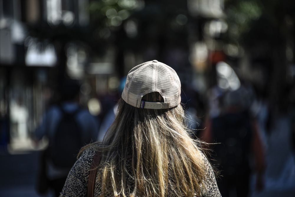 20240918 Gente caminando, una mujer usando gorro de espaldas, primavera, estado del tiempo, buen tiempo.