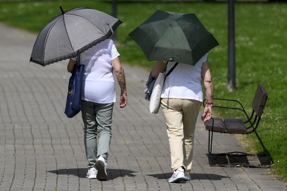 Dos personas se protegen del sol con paraguas este lunes en Oviedo, en una jornada en la que las temperaturas máximas en Asturias se han registrado en la capital, con 34,9 grados, y en España han sido de 36,7 grados en Mérida.