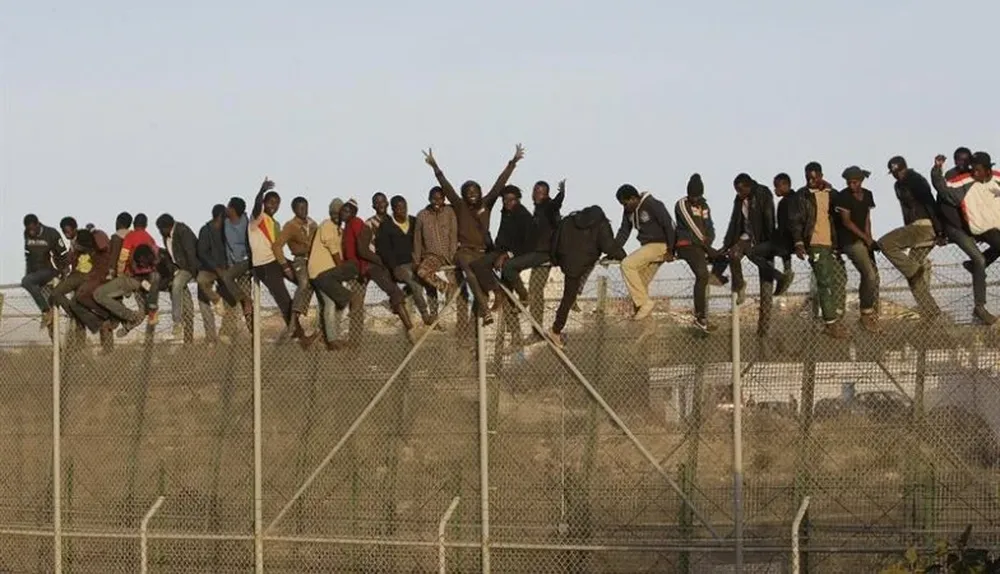 España. Inmigrantes encaramados a la valla de Melilla, frontera con Marruecos, intentando cruzar.