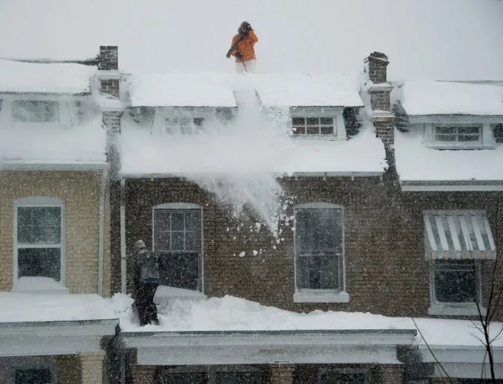 Gente limpia la nieve de los techos de sus casas en Washington