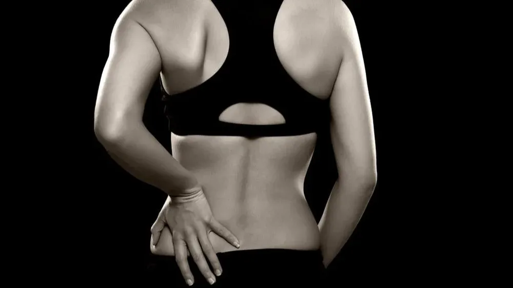 Una mujer padece de lumbalgia.