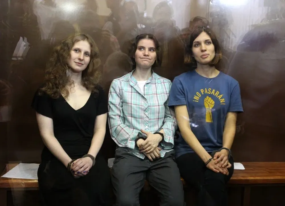 (FILES) In this file photo taken on August 17, 2012 in moscow, members of the all-girl punk band Pussy Riot Nadezhda Tolokonnikova (R), Maria Alyokhina (L) and Yekaterina Samutsevich sit in a glass-walled cage after being sentenced to a two-year prison after infuriated the Kremlin and captured world attention by ridiculing President Vladimir Putin in Russias main church. The European Court of Human Rights condemned Russia in two separate judgements on July 17, 2018 over its investigation into murdered journalist Anna Politkovskaya and its treatment of the protest group Pussy Riot. A case involved three members of Pussy Riot, the feminist punk group which made headlines worldwide in 2012 when the women were arrested for performing a protest song in a Moscow church titled Punk Prayer -- Virgin Mary, Drive Putin Away. The court concluded that Russia had violated their human rights by subjecting them to humiliating and intimidating treatment, not providing a fair trial and not allowing them freedom of expression. / AFP / -
