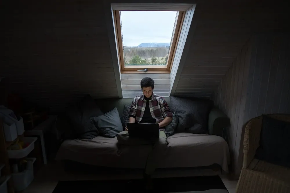 focused-young-man-using-laptop-in-mansard-room-4413745.webp