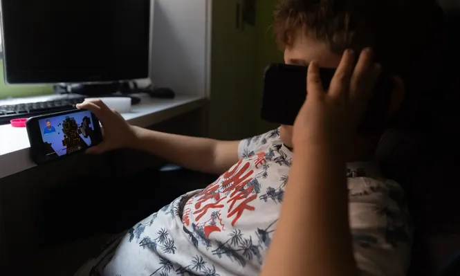 Un niño usa el teléfono móvil y una tablet.