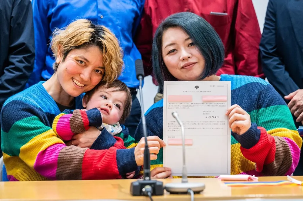 Mamiko Moda y Satoko Nagamura, junto con su hijo, sostienen el certificado de relación