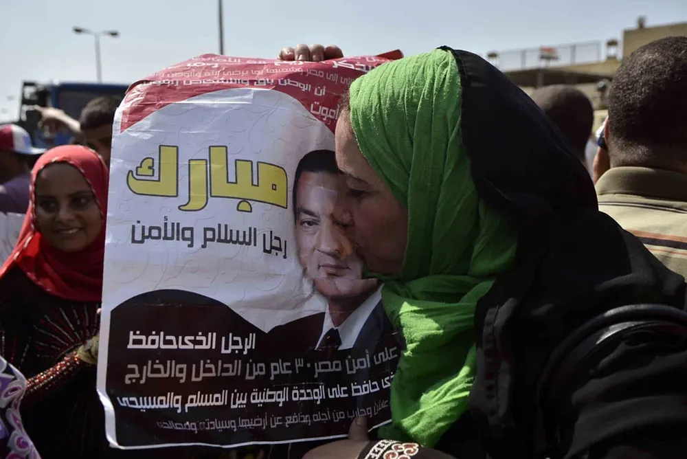 Una mujer besa una foto de Mubarak, ayer trasladado a un hospital donde tendrá arresto domiciliario