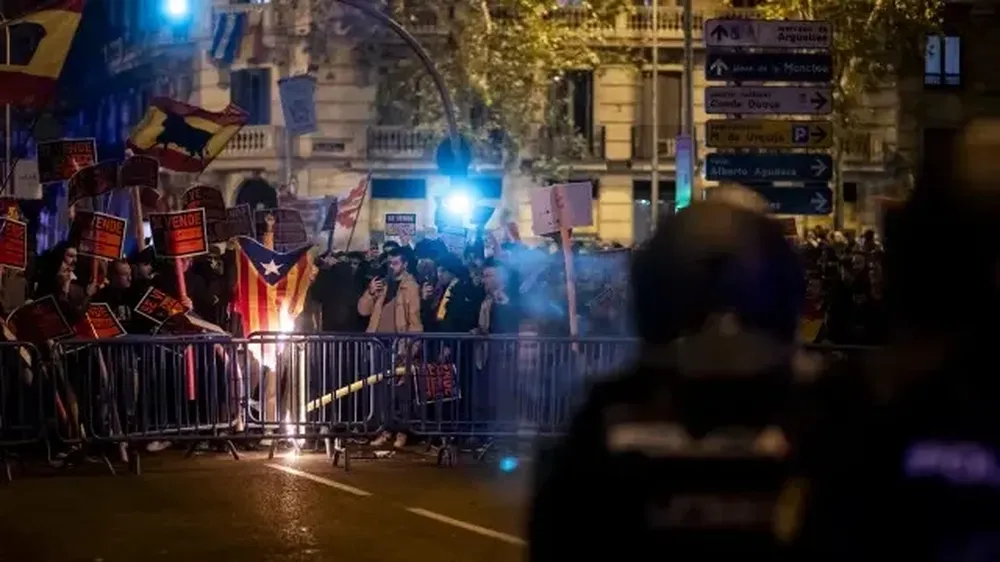 Decenas de manifestantes con carteles de se vende queman una estelada, durante la manifestación de este viernes contra la amnistía frente a la sede del PSOE en Ferraz