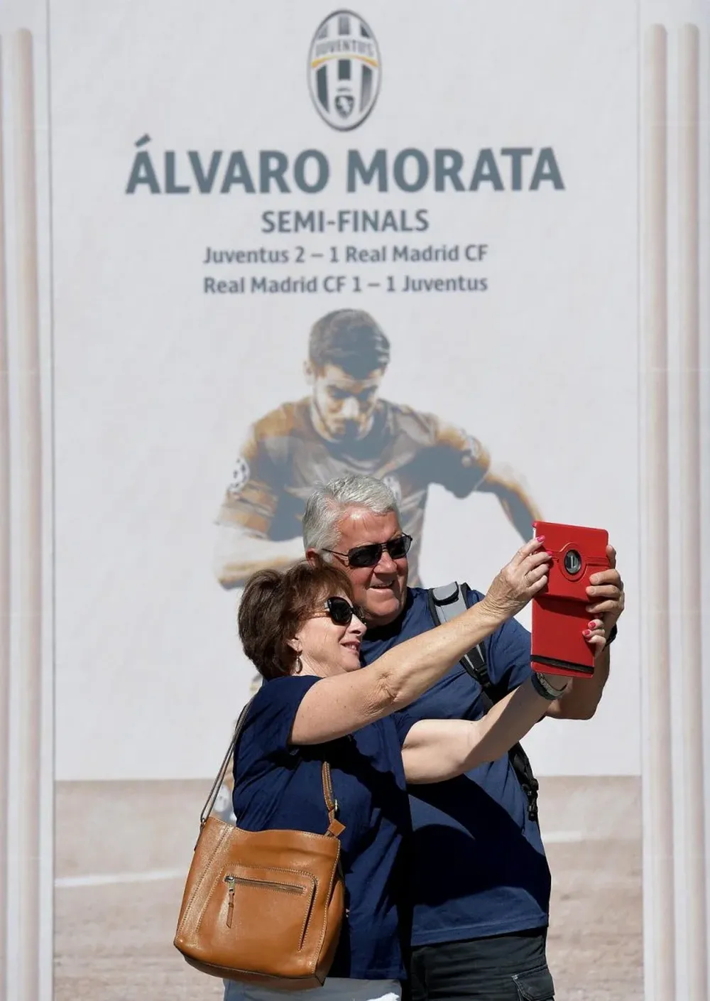 Una pareja de turistas se toma una selfie frente a una fotografía de Morata en Berlin.