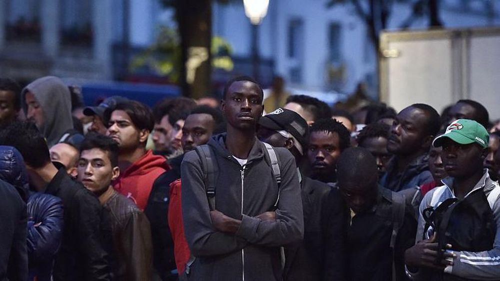 Un grupo de migrantes espera antes de ser evacuado de un campamento improvisado en París, Francia.